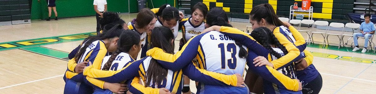 A group of female Fresno Unified volleyball players huddle up.