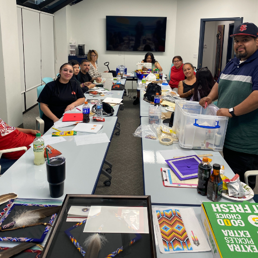 group of people around a table beading their graduation caps.
